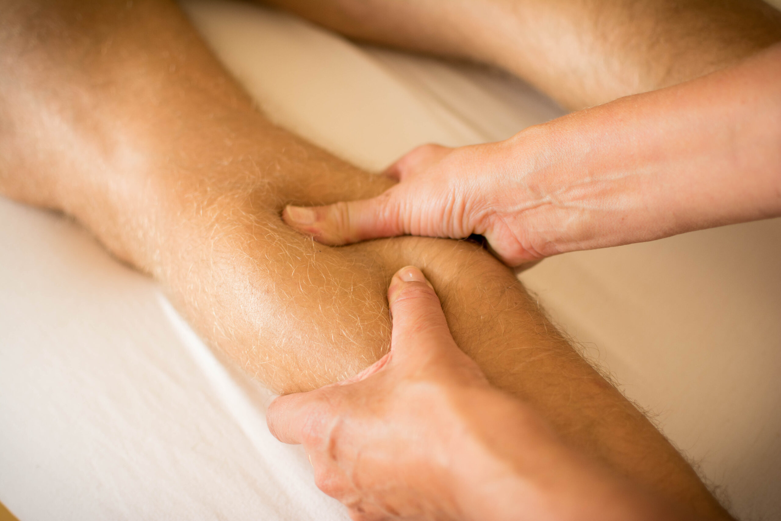 Individual receiving soft tissue massage to the calf during an in-home physical therapy session